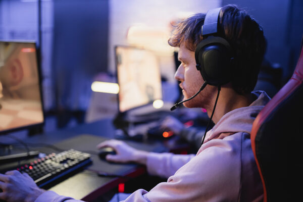 Side View Of Young Gamer In Headphones Playing Computer Game In Cyber Club,stock Image