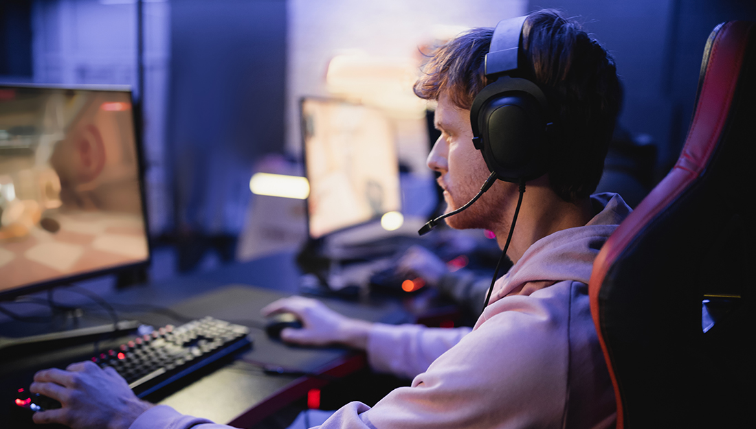 Side view of young gamer in headphones playing computer game in cyber club,stock image