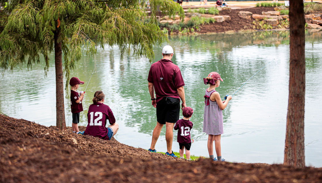 parents and their three young children dressed in Texas A&M fan gear spend time in nature at Aggie Park