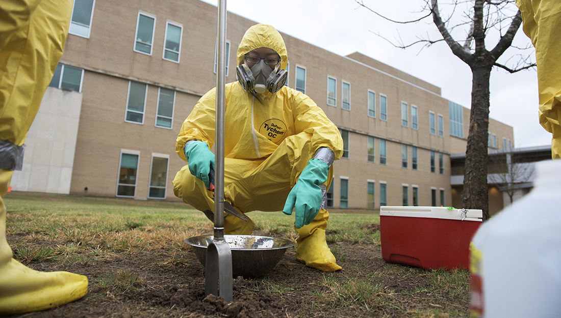 field researcher wears hazmat suit while collecting soil samples