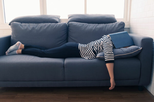 Woman Naps On A Couch With Her Head Under A Book