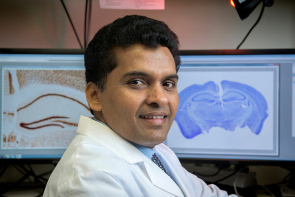 D. Samba Reddy Sits In Font Of A Computer Monitor In A Lab