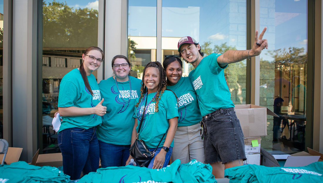 Group of people wearing teal Suicide Awareness Month t-shirts pose for a photo together