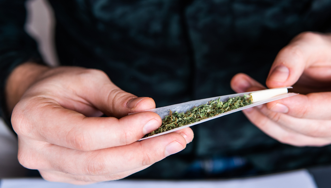 Man preparing and rolling marijuana cannabis cigarette