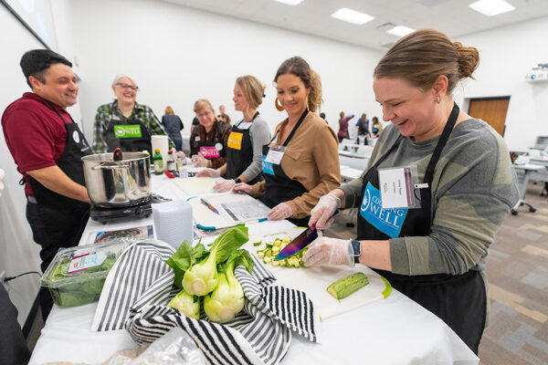 people wearing aprons prepare healthy food at a community facility