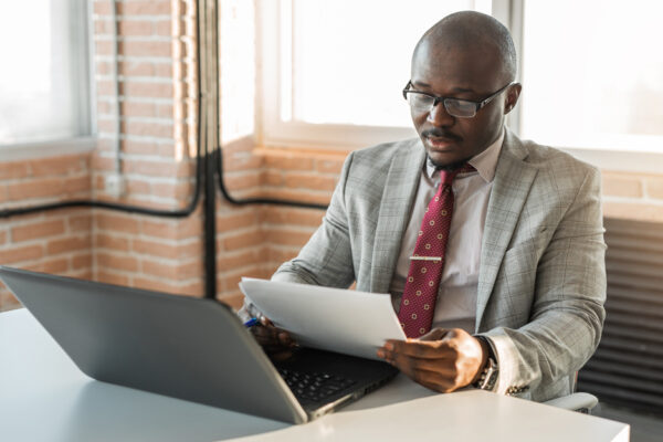 Middle-aged Man Works On A Laptop, Reviews Papers