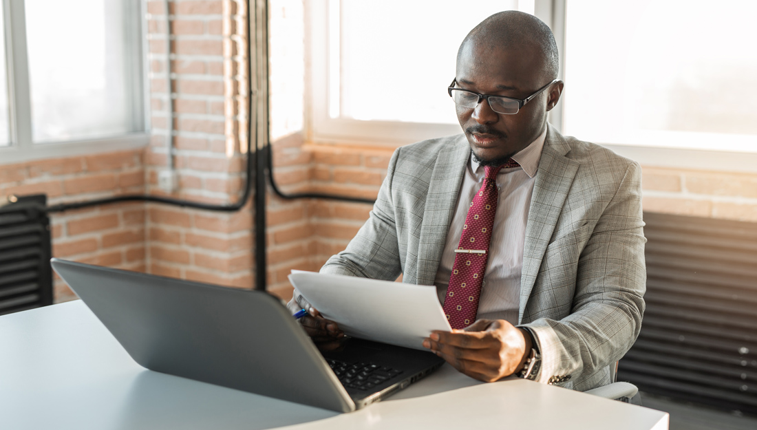 middle-aged man works on a laptop, reviews papers