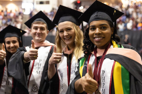 Adults Wearing Graduation Regalia Holding Their Thumbs Up