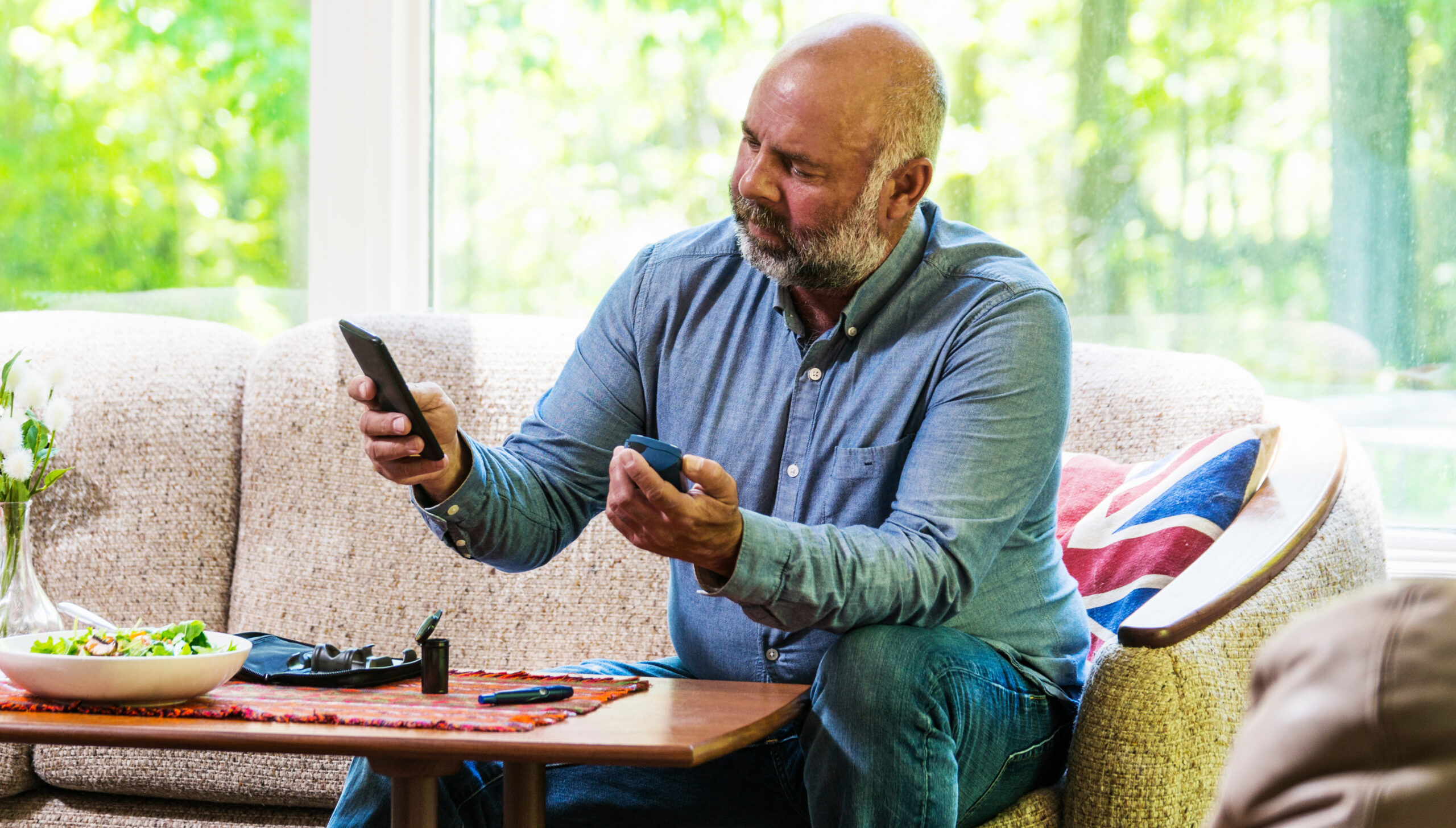 Mature diabetic man testing his blood sugar and using a smartphone