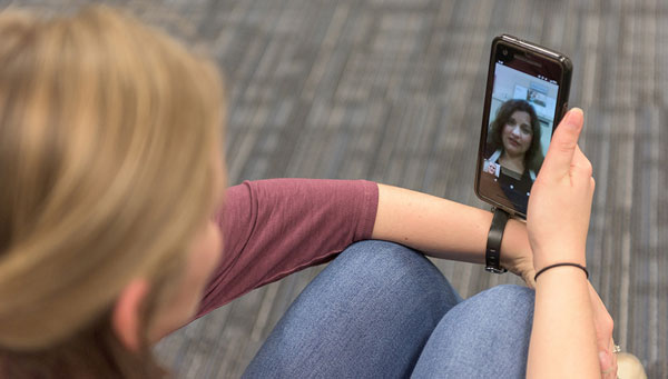 young woman video chats with a health care provider on a cell phone