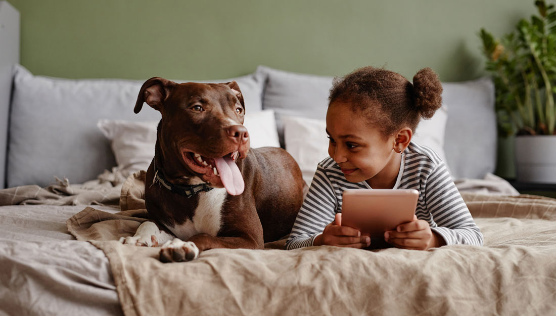 girl lying on bed with big pet dog