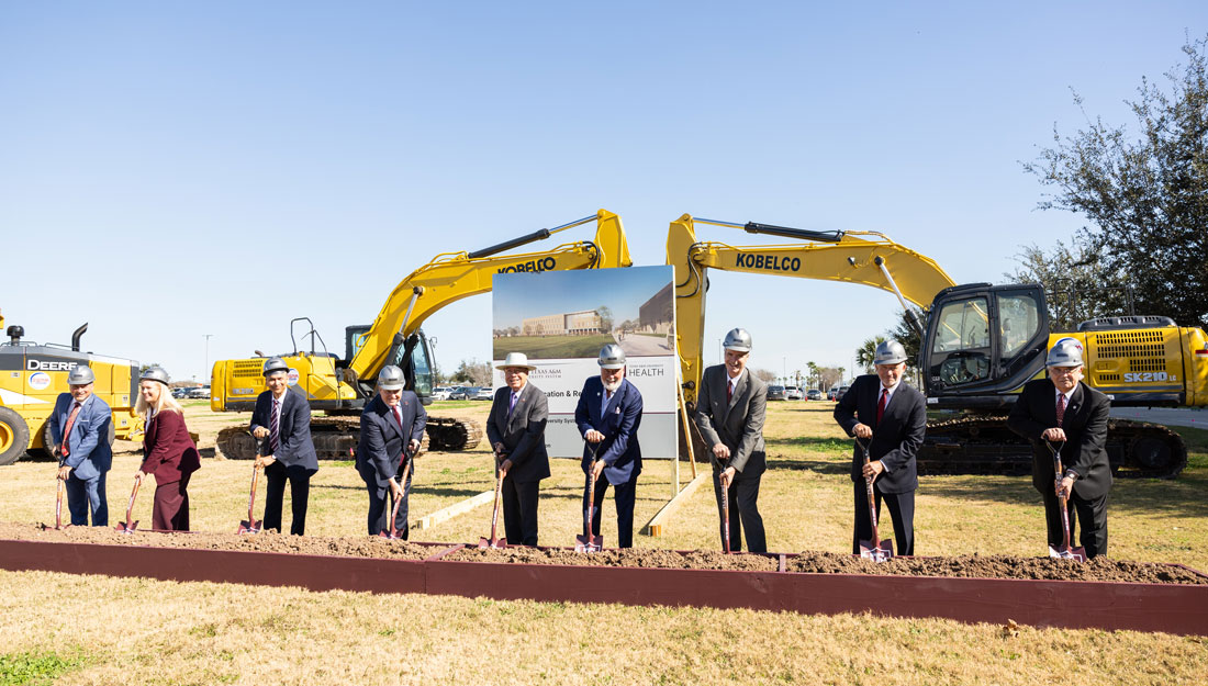 men and women in suits take part in a shovel ceremony