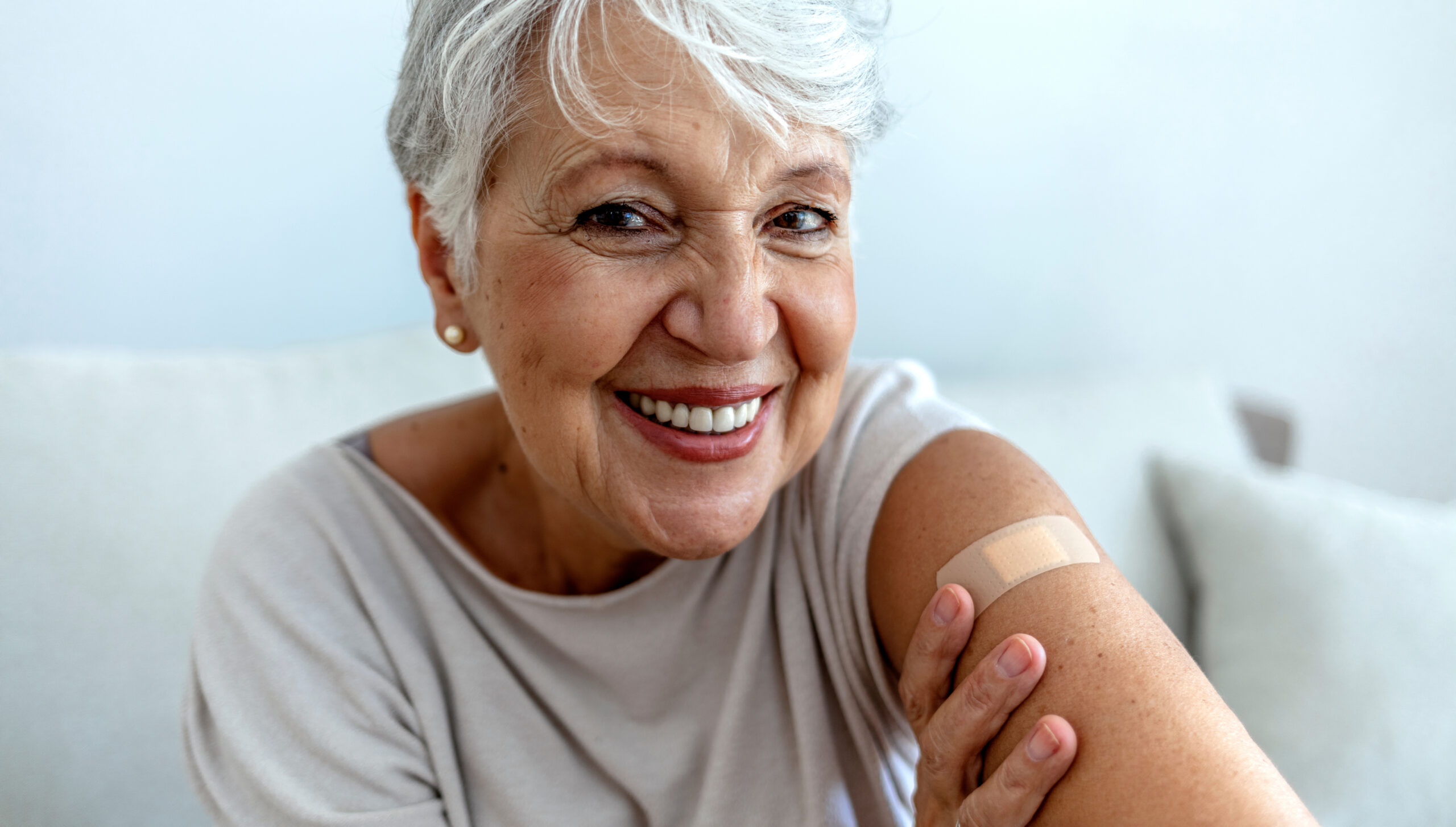 Vaccinated woman with bandage on arm - COVID-19 vaccines