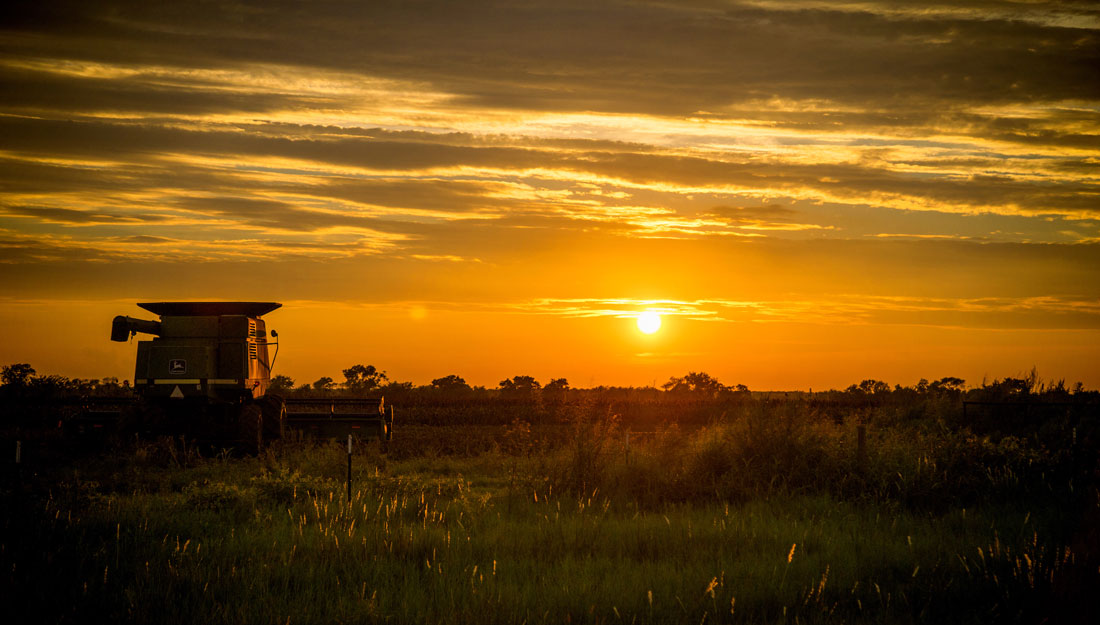 sunset over a farm with a tractor in the foreground. Rural health