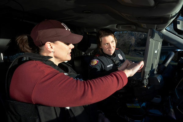 mental health counselor and police officer sit together in a police unit