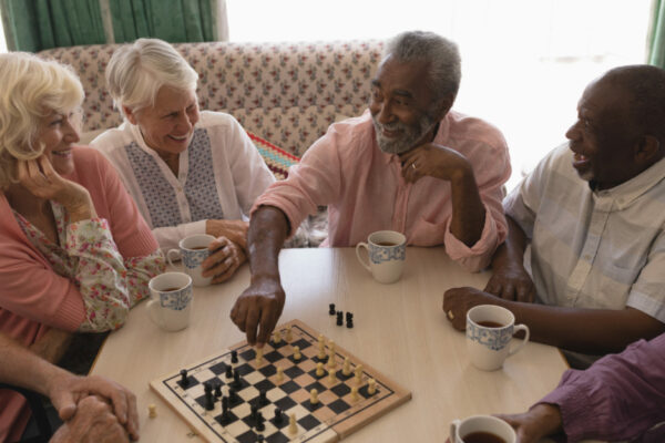 Group Of Senior People Playing Chess In Living Room