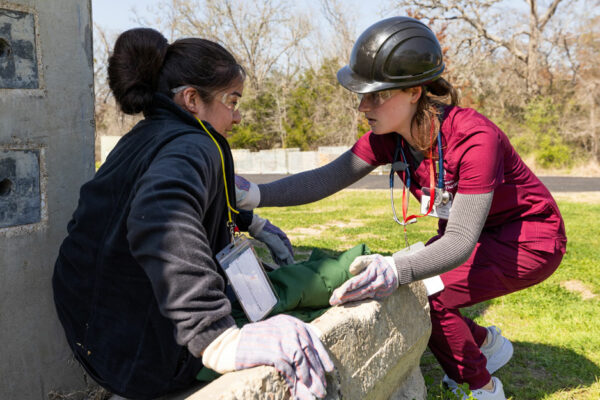 Nursing Student In Maroon Scrubs Assists Another Student Playing The Part Of A Disaster Victim