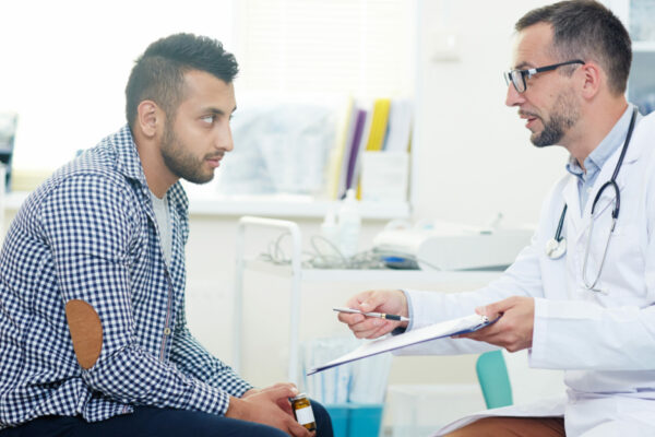 Man Visits With Doctor In A Clinic Exam Room