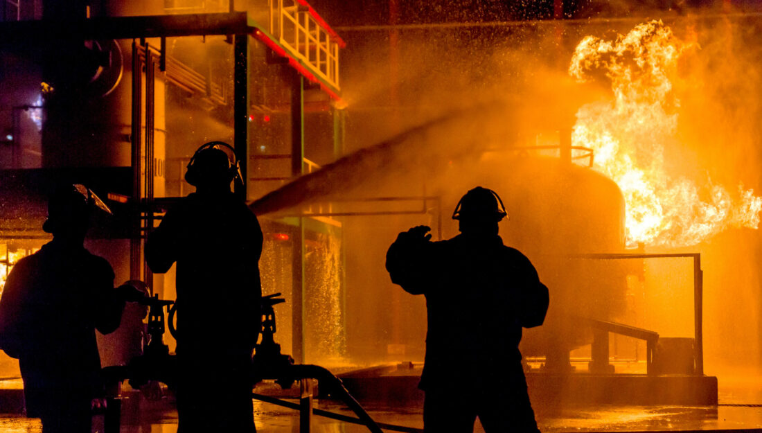 Firemen using water from hose for fire fighting