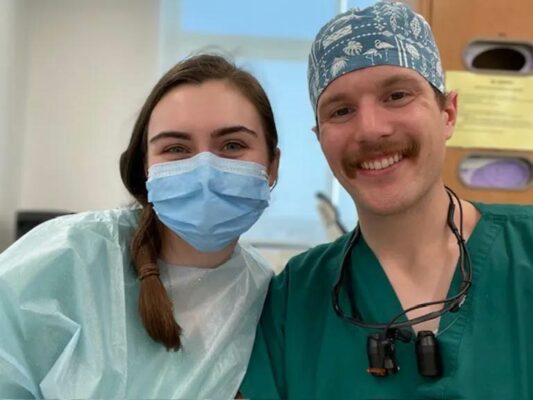 man and woman wearing dentistry scrubs take a selfie