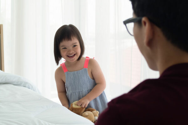 A Child With Down Syndrome Smiles At Her Father