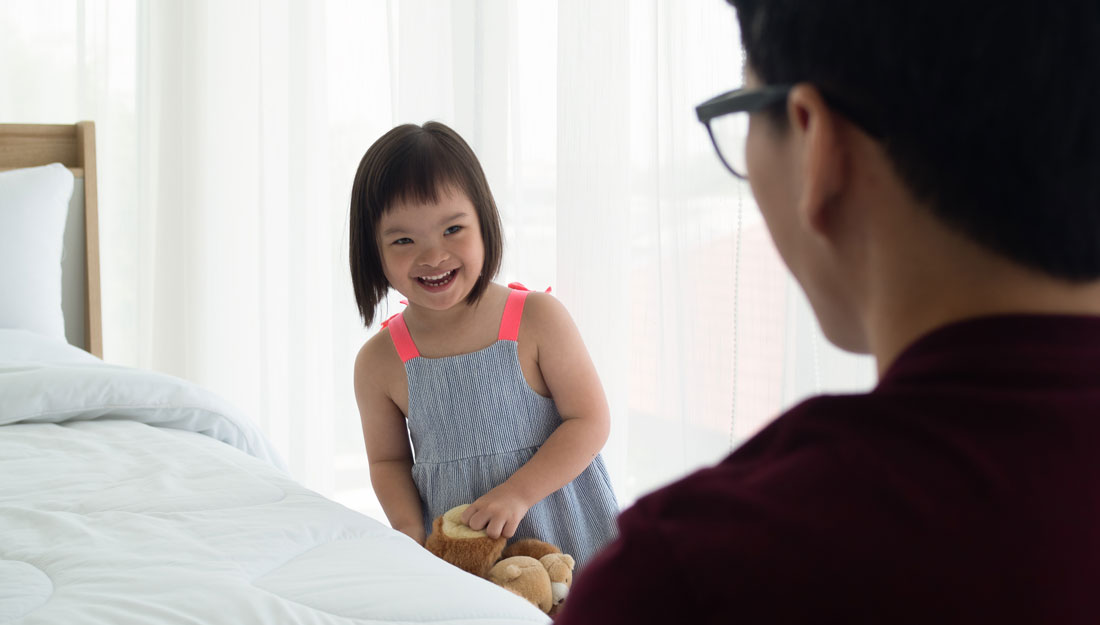 a child with Down syndrome smiles at her father