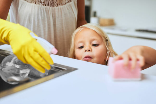 A Mother And Her Little Daughter Cleaning A Kitchen Surface Together At Home