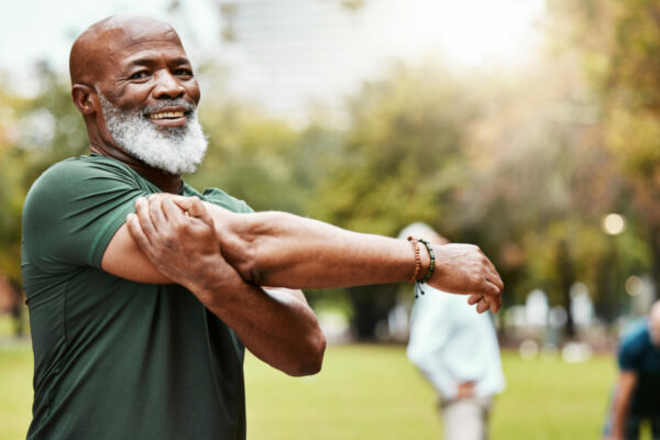 Smiling Older Man Stretches His Arms As If About To Engage In Physical Activity In An Outdoor Setting