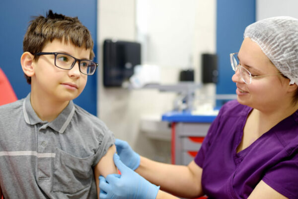 A Little Boy Is Being Vaccinated. A Child Is Very Afraid Of The Injection. Schoolkid Nervous During Scheduled Vaccination. Close Up