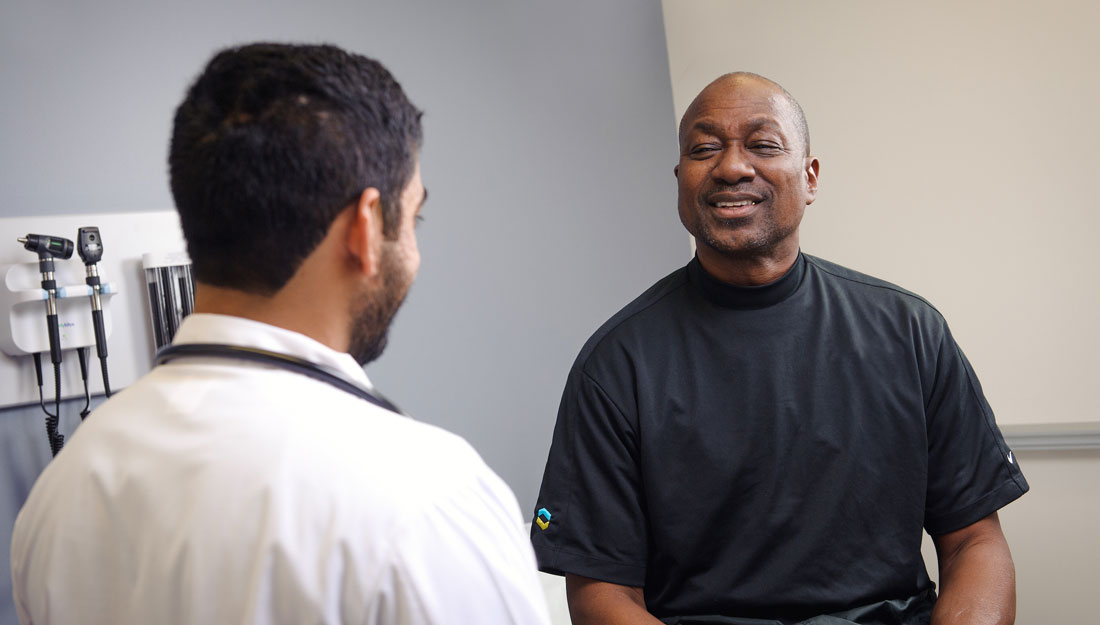 man talks with physician in an exam room