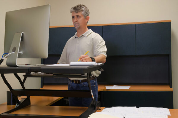 Man Works On Computer At A Standing Desk Workstation