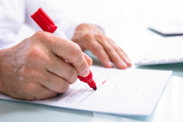 Person Marking Errors With A Red Marker On A Document