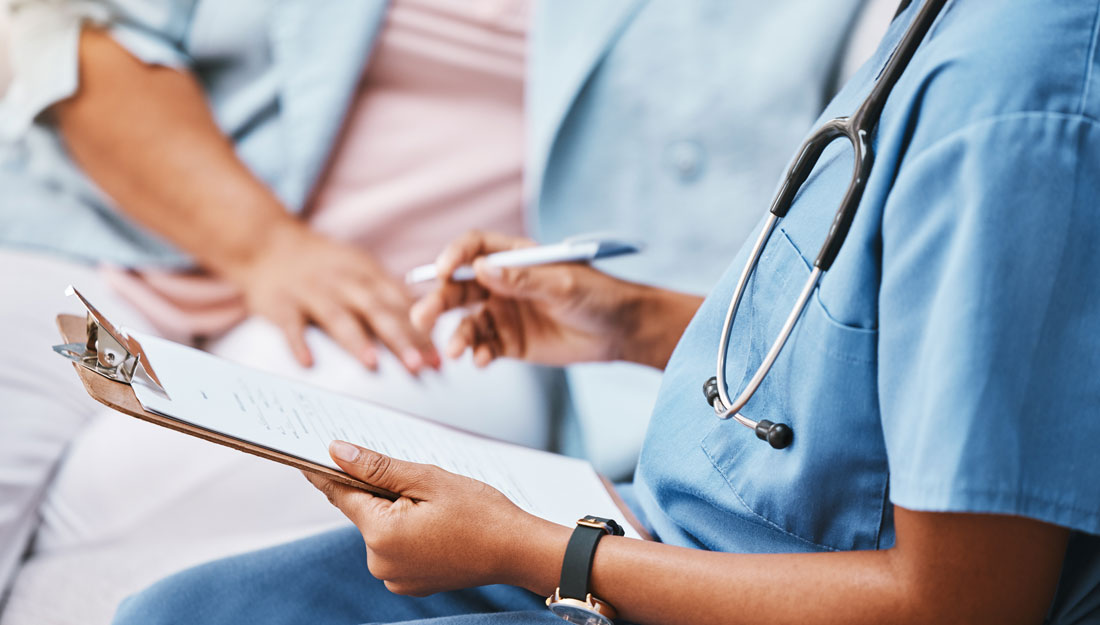 health care professional holds a clipboard, sits beside a patient, discusses health care plan and prior authorization