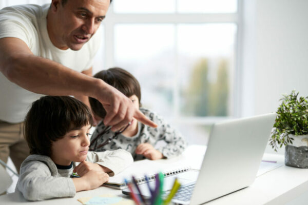 Father Helps His Two Young Children Work On A Computer