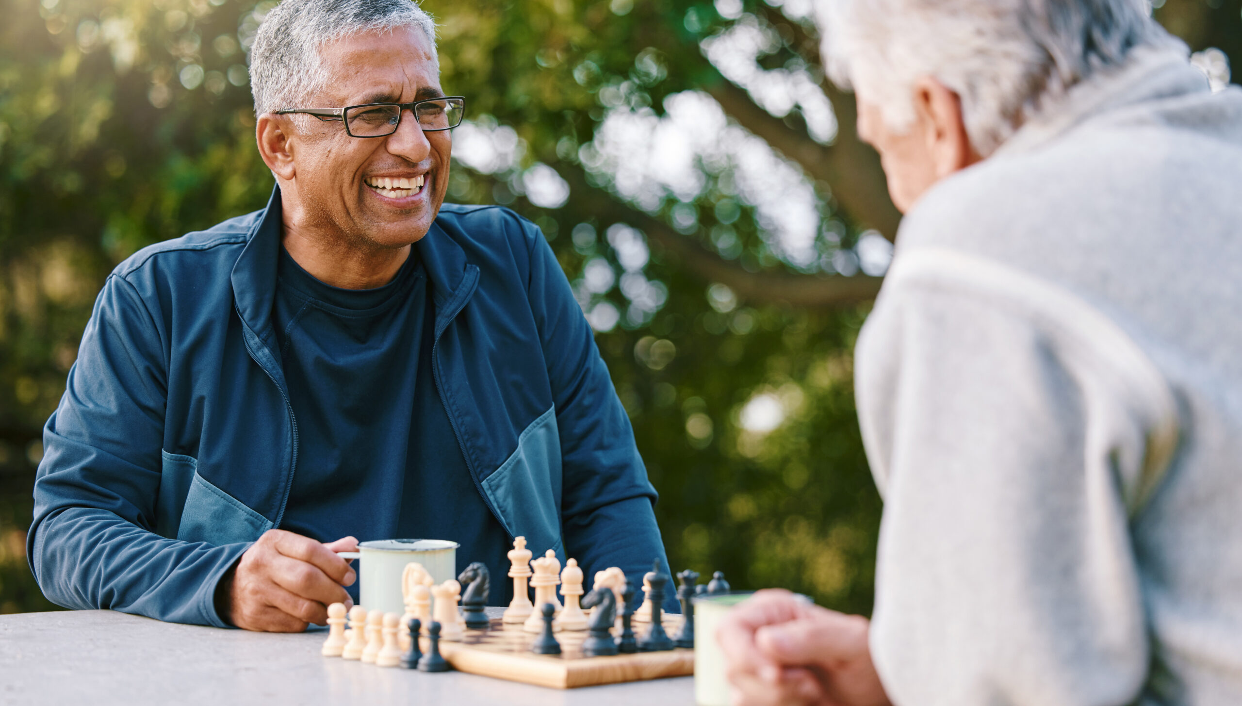 Two older men play chess together outdoors