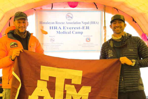 Two Men Hold A Texas A&M Flag At The Mount Everest Base Camp