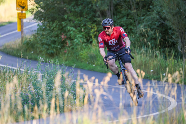 Pat Monday rides in the LoToJa bike race, wearing a maroon bicycle kit with Texas A&M Medicine branding