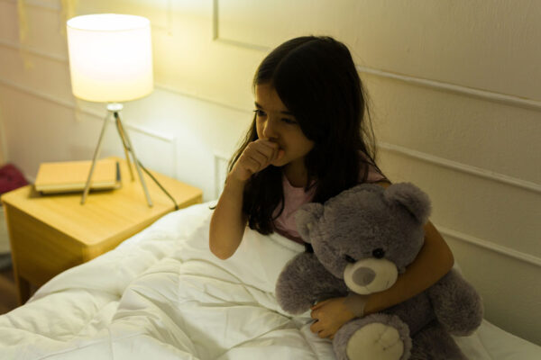 Girl With Her Teddy Bear, Coughing While Trying To Sleep In Her Bedroom At Night