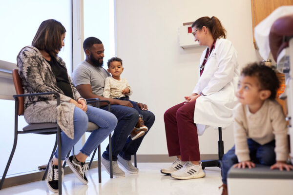 Mother, Father And Two Toddler Sons Visit With A Texas A&M Physician Inside A Clinic Exam Room