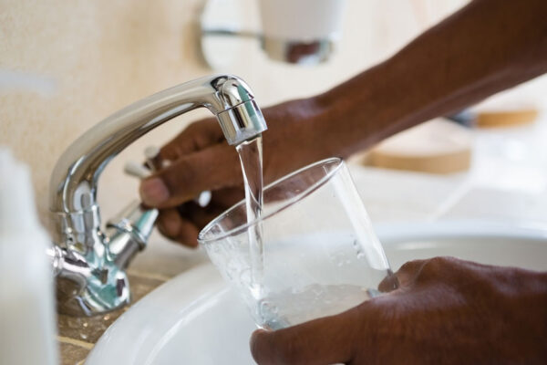 Person Fills A Drinking Glass With Water From A Faucet