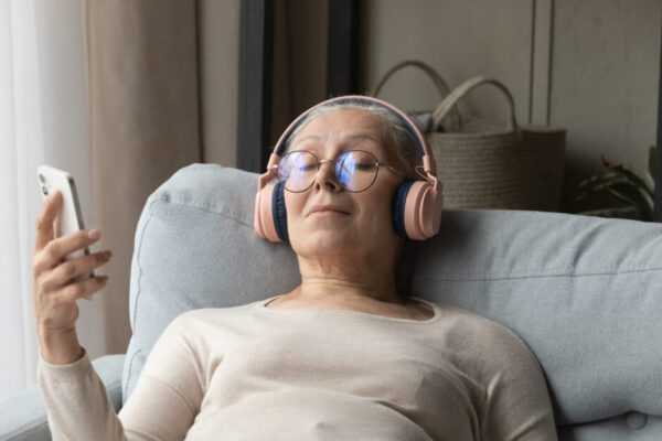 Calm Senior Lady In Wireless Headphones Listening To Relaxing Music