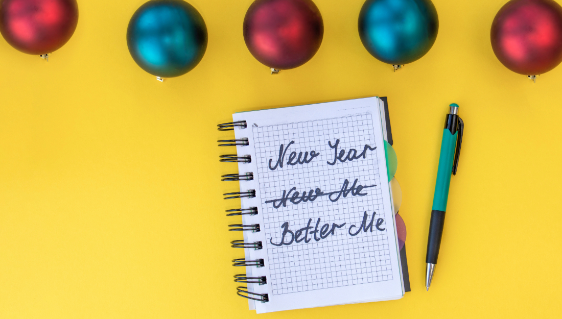 Yellow backgruond with blue and red Christmas bobbles and a notepad that reads "New Year, New Me" with "New Me" crossed out and "Better Me" written instead.