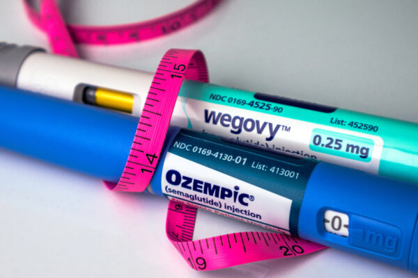 A Hot Pink Tape Measure Wrapped Around An Ozempic And Wegovy Pen Laying On A Table