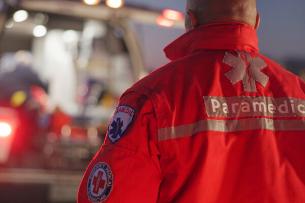 Man Wearing A Paramedic Jacket Walks Toward An Ambulance