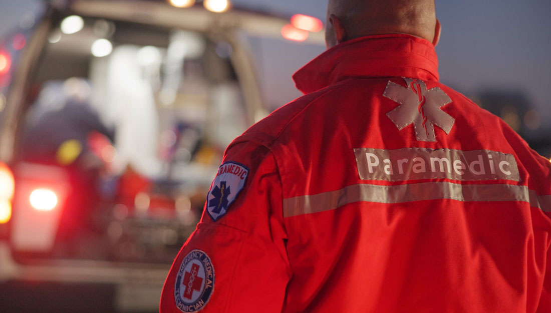 Man wearing a paramedic jacket walks toward an ambulance