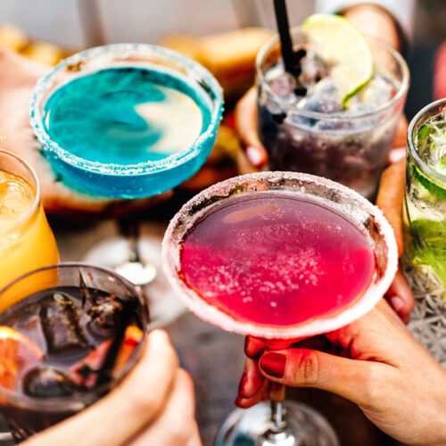 People's Hands Toasting Multicolored Fancy Cocktails