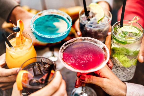 People's Hands Toasting Multicolored Fancy Cocktails