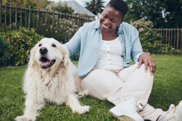 Woman Sits In The Grass Next Her Dog, Petting It Affectionately