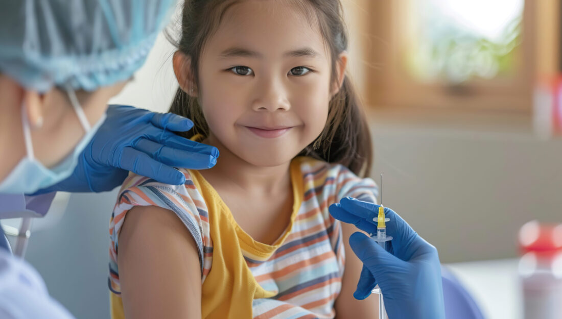 Smiling little girl in doctor's office is receiving a vaccination.