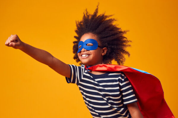 boy with a big smile dressed as superhero against orange background